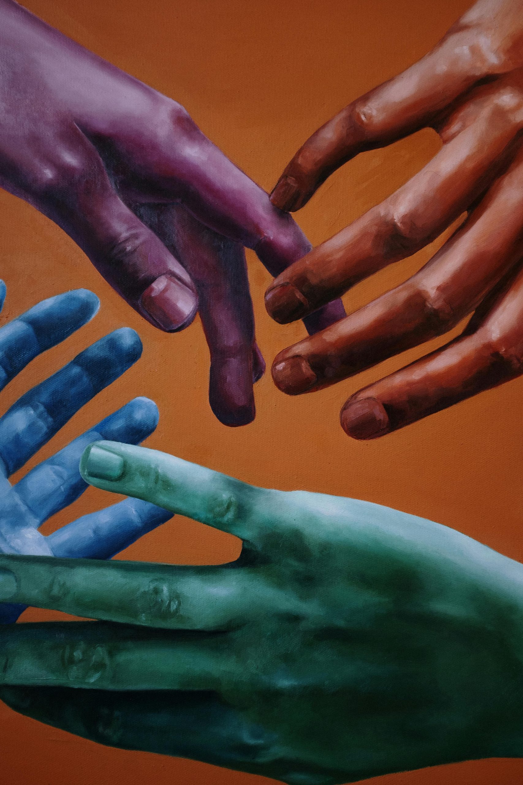 Artistic portrayal of multicolored hands on a vibrant orange background, symbolizing unity and diversity.